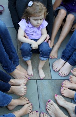 Rett Syndrome Awareness Month / Rett Syndrome News / Photo of Cammy wearing a purple shirt and sitting in a circle with her cousins, whose toenails are all painted purple.