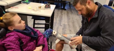working from home | Rett Syndrome News | Bill puts his daughter's ankle-foot orthoses on before she leaves for school.