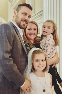 Rare Disease Day | Rett Syndrome News | A family photo shows parents Bill and Jackie with their daughters Cammy and Ryan. Ryan is dressed in white for her first Communion.