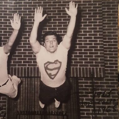 Rett Syndrome News | An old photo shows Jackie's dad, Joe Corrado, at the University of Illinois in 1965. He is wearing a white Superman t-shirt and posing with his arms up like he's flying.