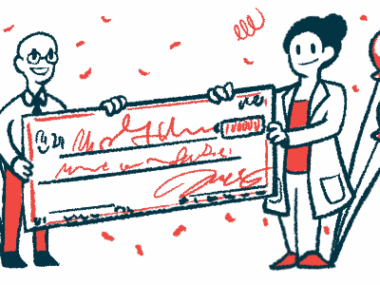 Two people surrounded by balloons hold up an oversized check, signifying a donation or award.