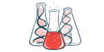 Two bottles, each containing a strand of DNA, are pictured behind a third bottle filled with red liquid.